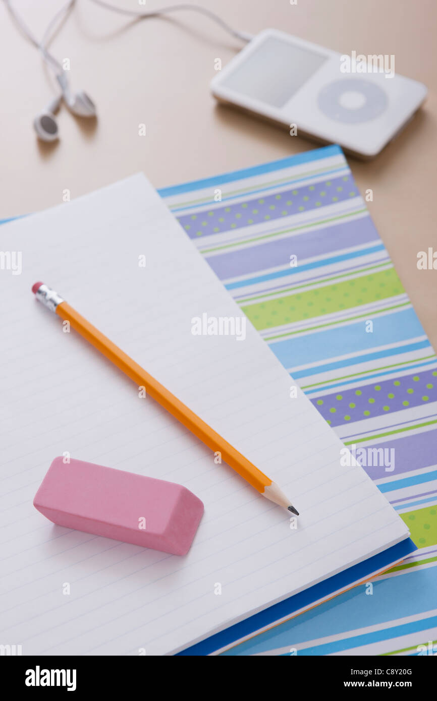 Pencil and rubber on notebook, mp3 player in background Stock Photo