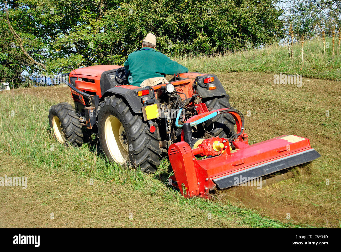 Small farm tractor bush hogging on a grass field in Trentino Alto Adige