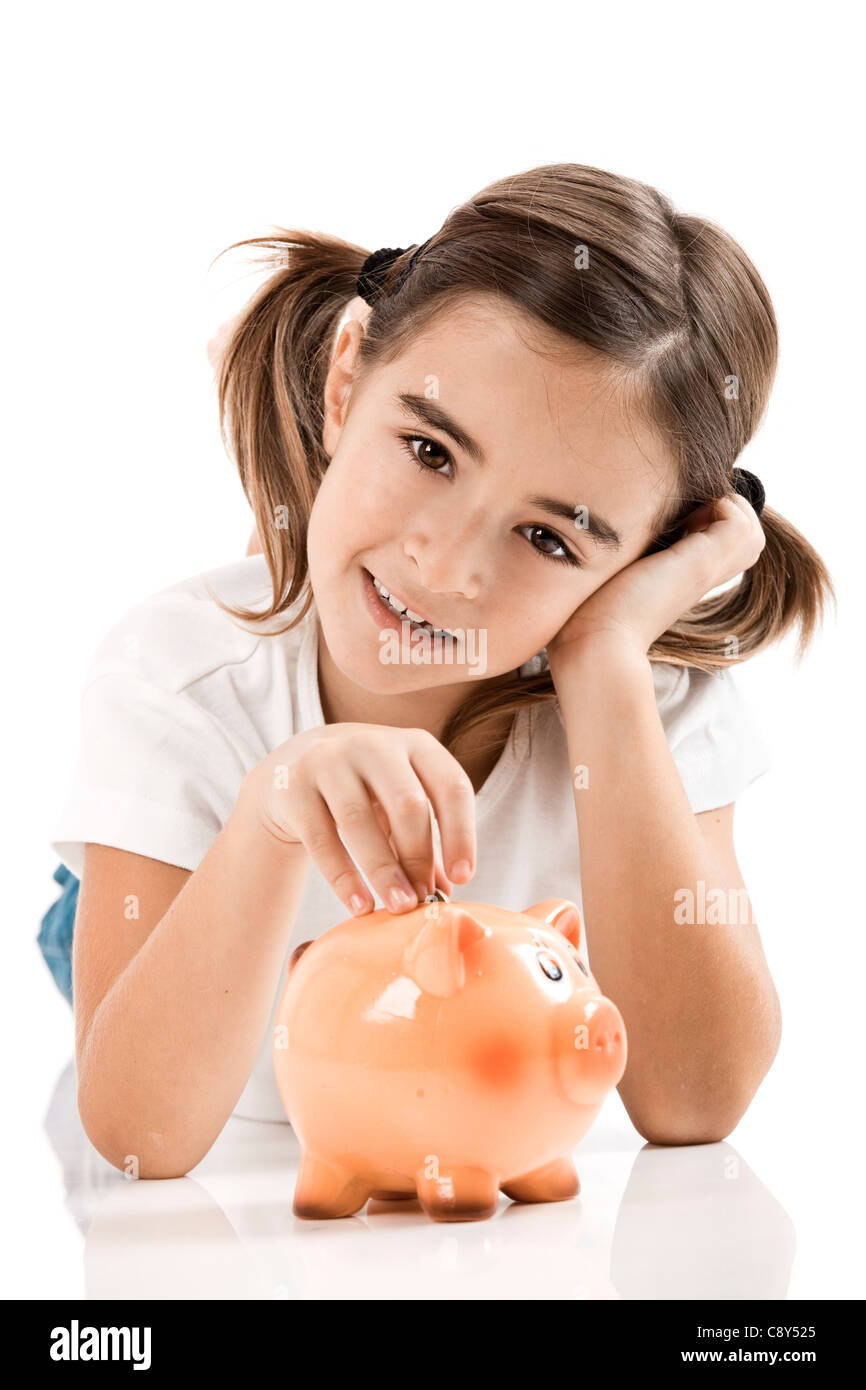 Little girl lying on floor and inserting a one euro coin on the piggy ...