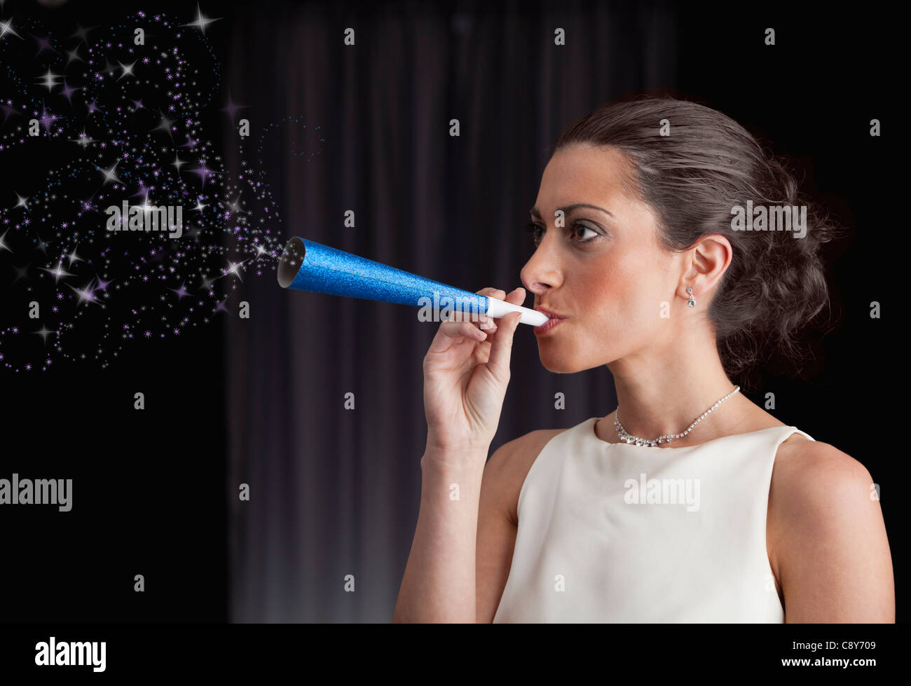 Woman blowing stars out of paper blow horn Stock Photo - Alamy