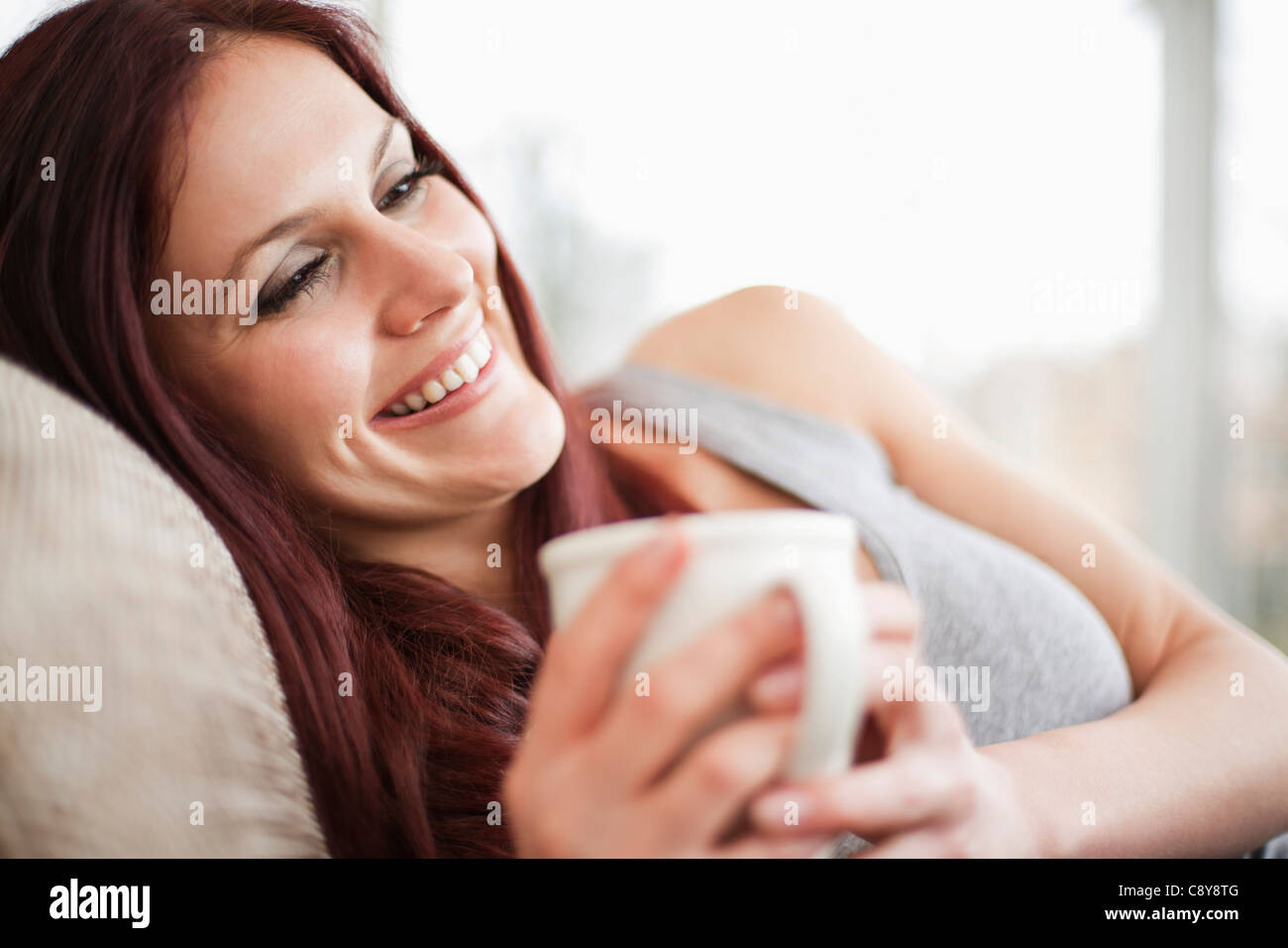 portrait of young woman with coffee cup relaxing on sofa Stock Photo ...