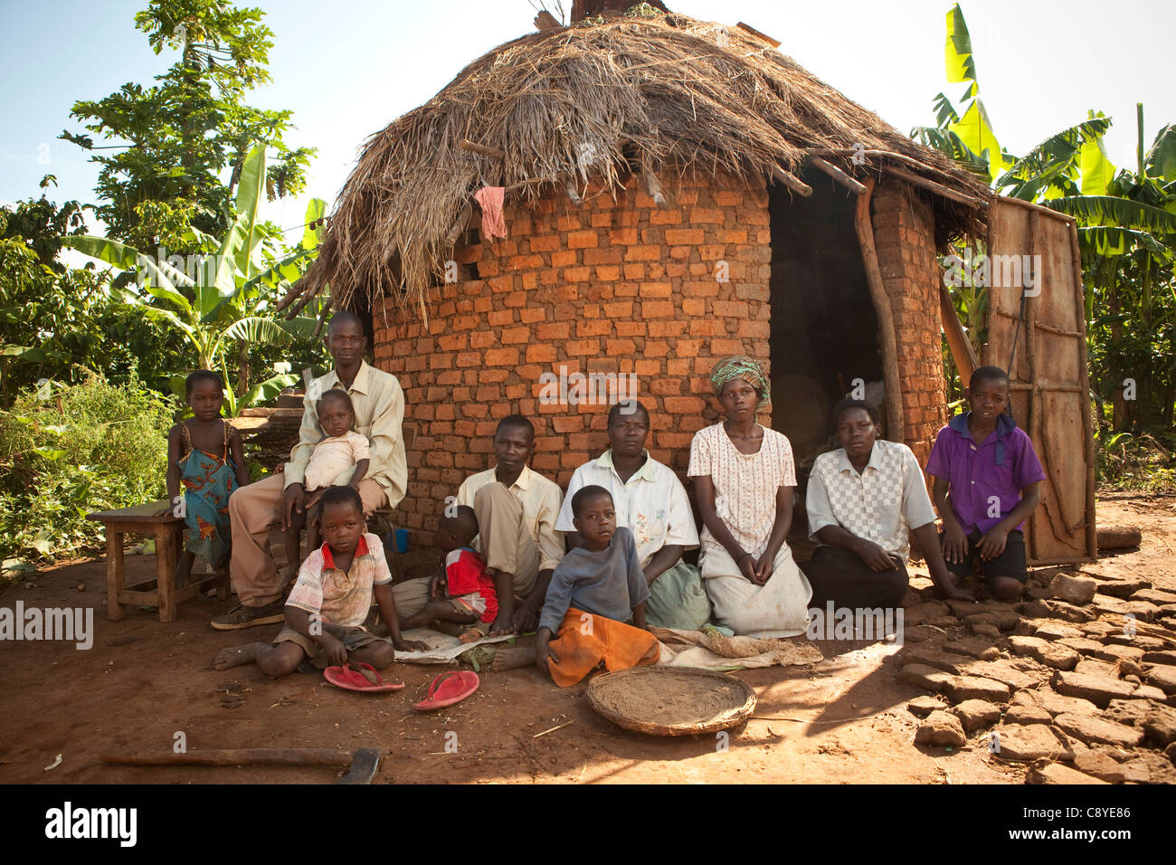 A family sits together outside their kitchen in Nsinze Village, Namutumba District, eastern Uganda. Stock Photo