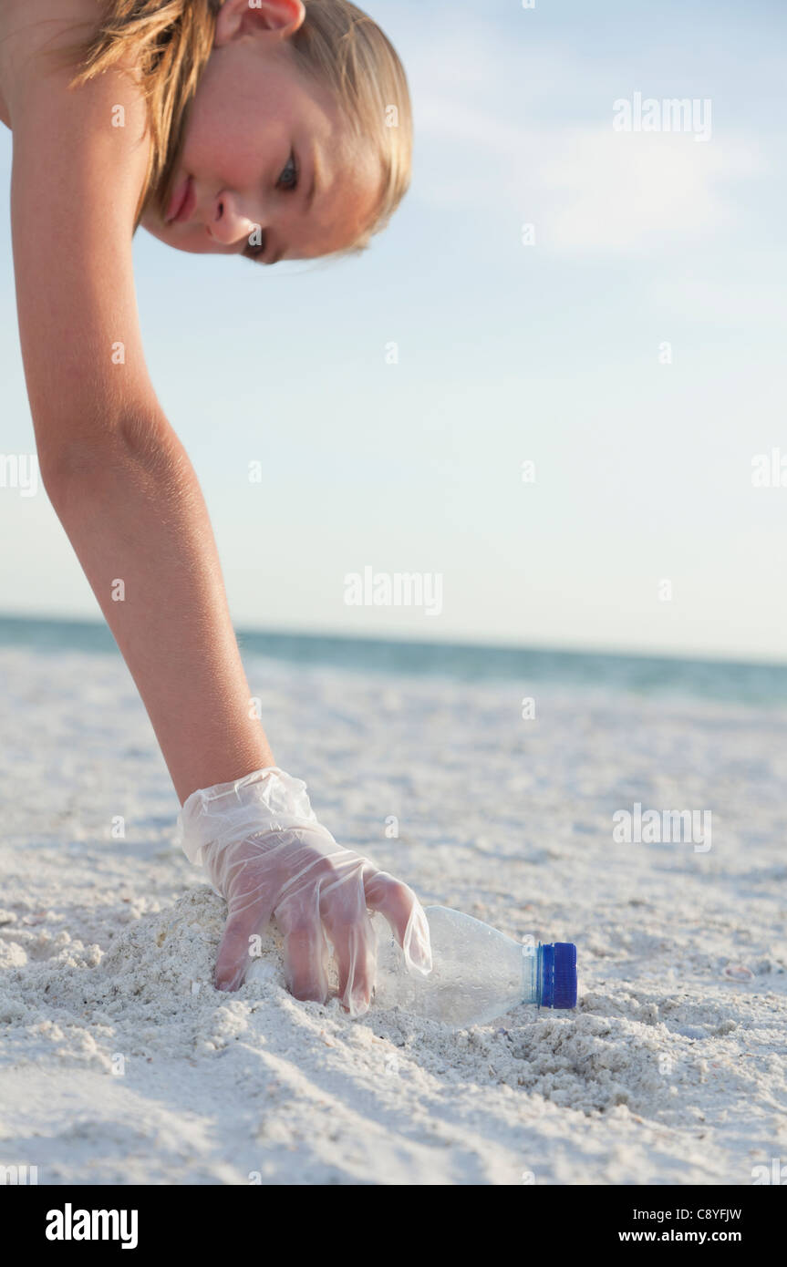 USA, Florida, St. Petersburg, Cose-up of girl (10-11) cleaning beach, reaching for plastic bottle Stock Photo