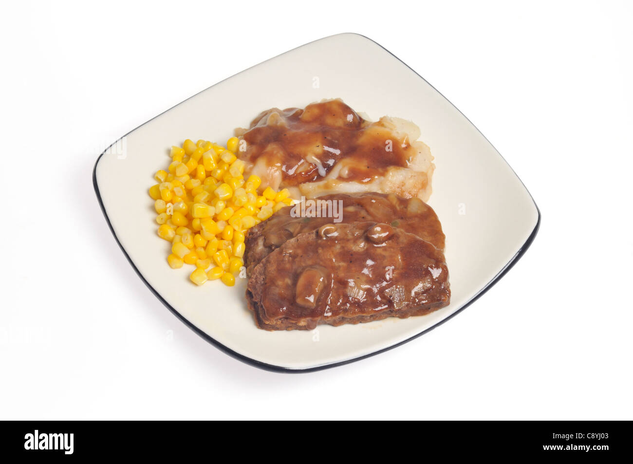 Slice of cooked meatloaf meal with mushroom gravy, mashed potatoes and sweet corn on white plate on white background, cutout. Stock Photo