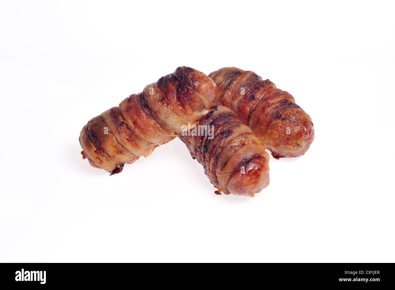 Hot, cooked Piggies in blankets, also known as pigs in a blanket, sausages wrapped in bacon on white background cutout. Stock Photo