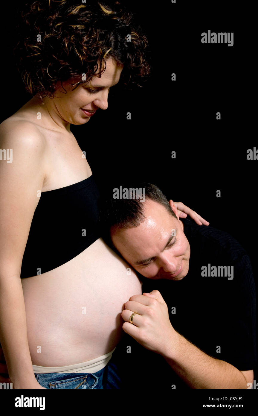 A maternity image of a married couple, the man is pretending to knock on the woman's belly to see if anyone is home. Stock Photo