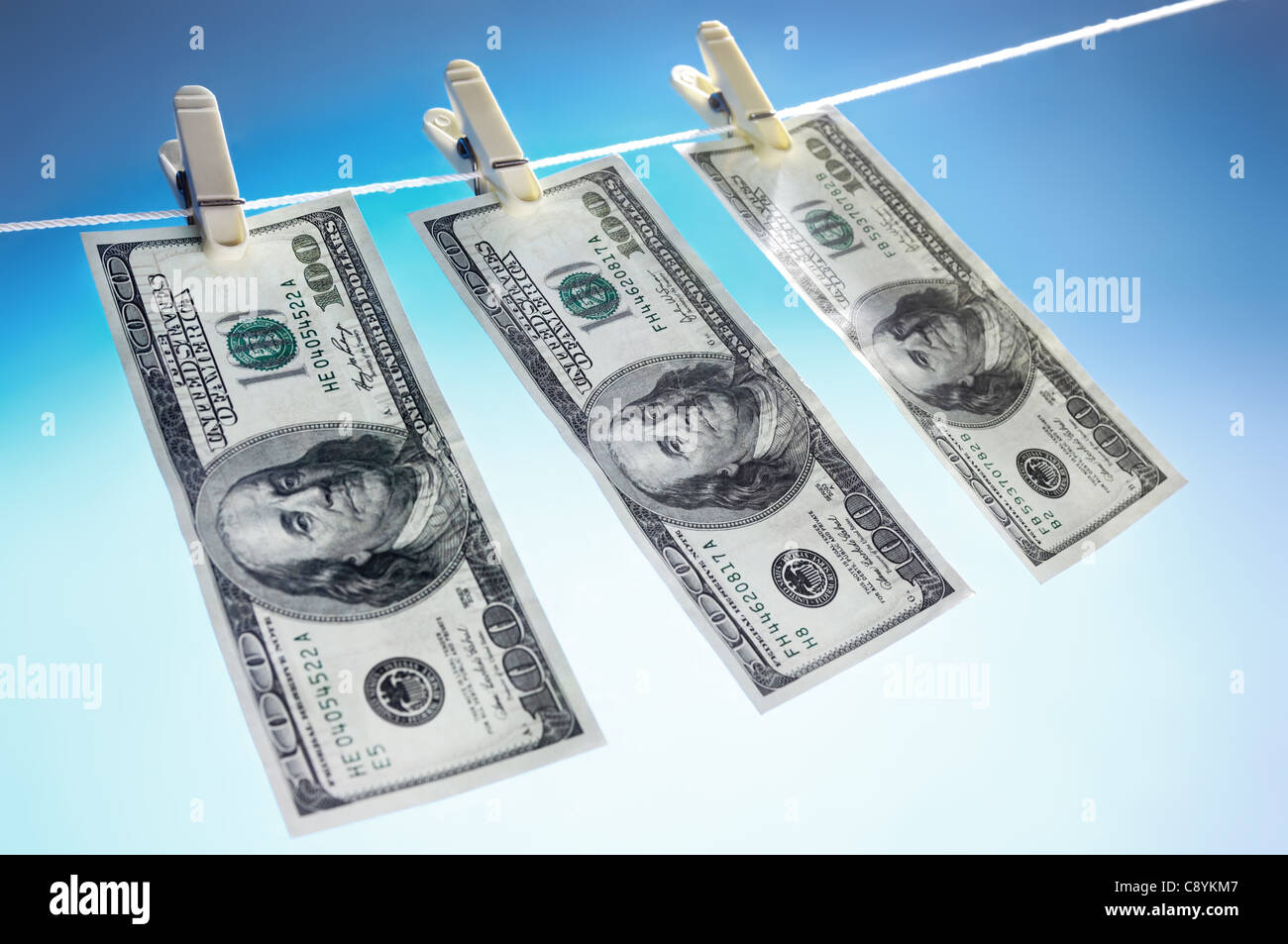 Hundred dollar bills drying on a clothes line isolated on blue sky background Money laundering concept Stock Photo