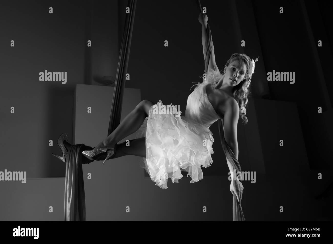 Female model aerial silks acrobat posing in a wedding dress in the air Stock Photo