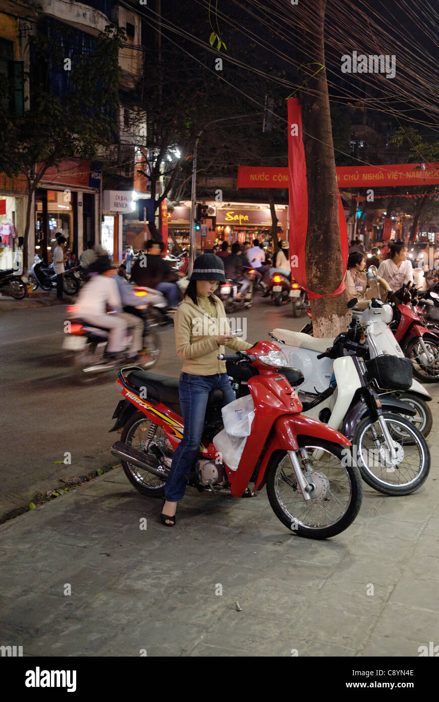 Asia, Vietnam, Hanoi. Hanoi old quarter. Using a mobile phone while being on the motorbike.... Stock Photo