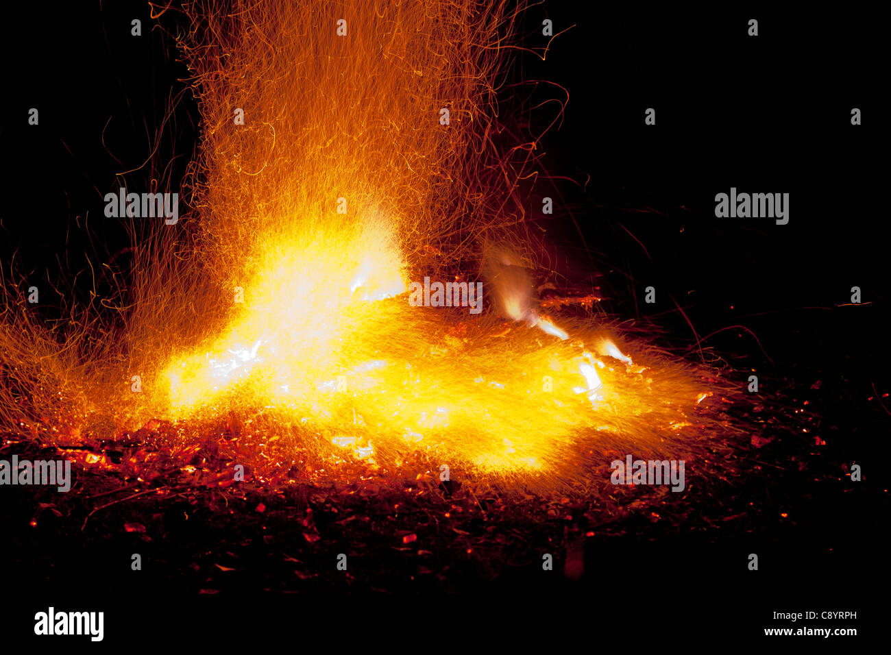 Fire with flames and sparks. Intense orange, yellow glow of bonfire against a black night background. Stock Photo