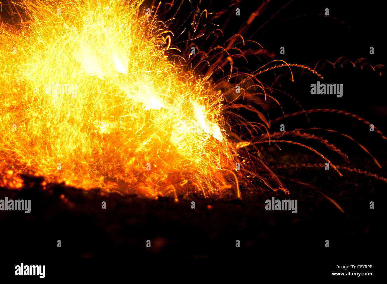 Fire with flames and sparks. Intense orange, yellow glow of bonfire against a black night background. Stock Photo