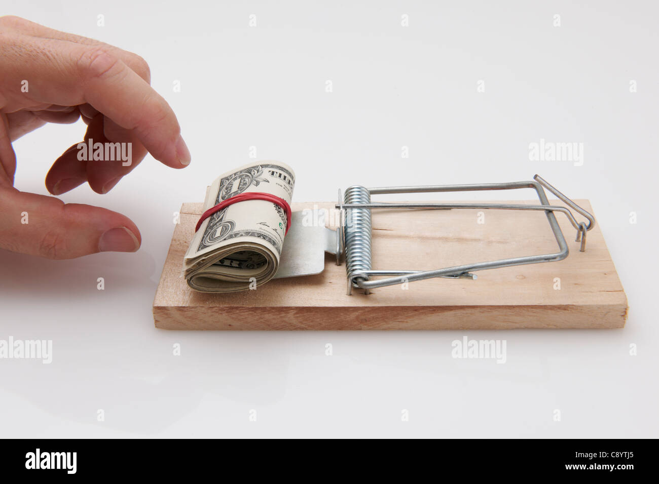 Male hand taking rolled up dollar bills from mousetrap Stock Photo