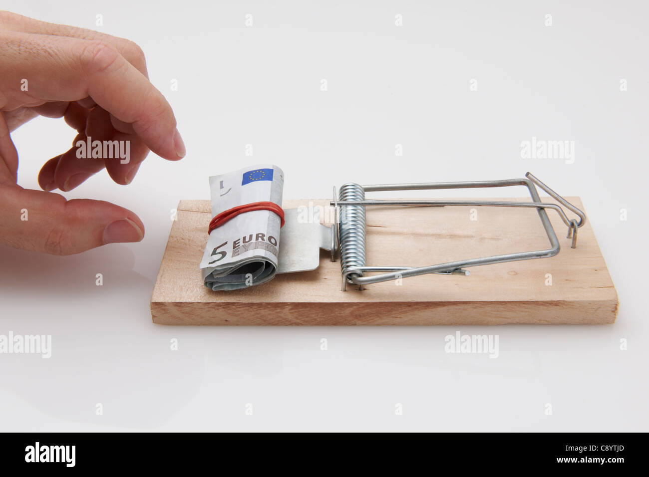 Male hand taking rolled up euro bills from mousetrap Stock Photo