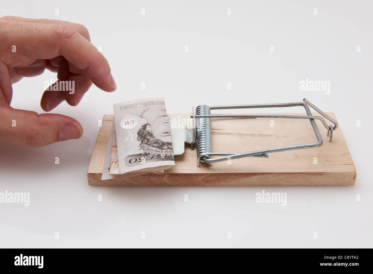 Male hand taking fifty pound note from mousetrap Stock Photo