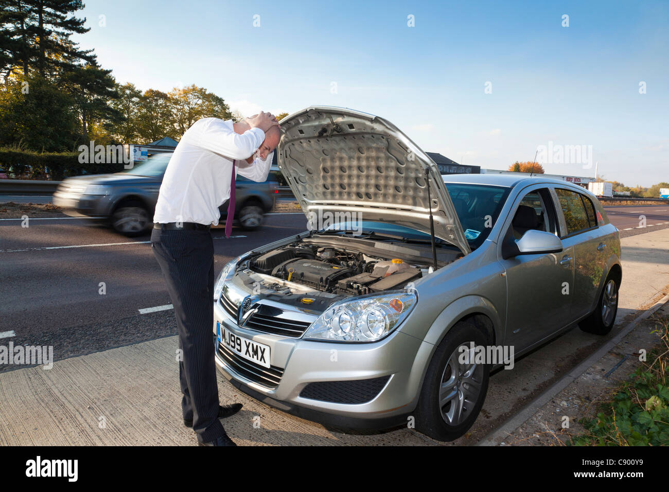 man with broken down car along motorway Stock Photo