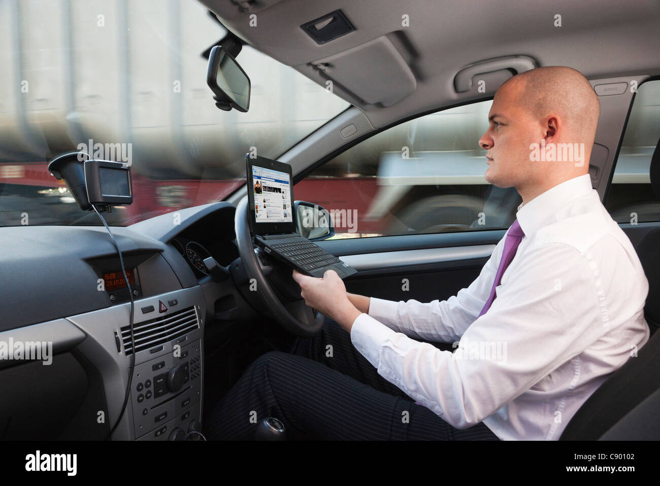 man using laptop computer whilst driving car on motorway Stock Photo