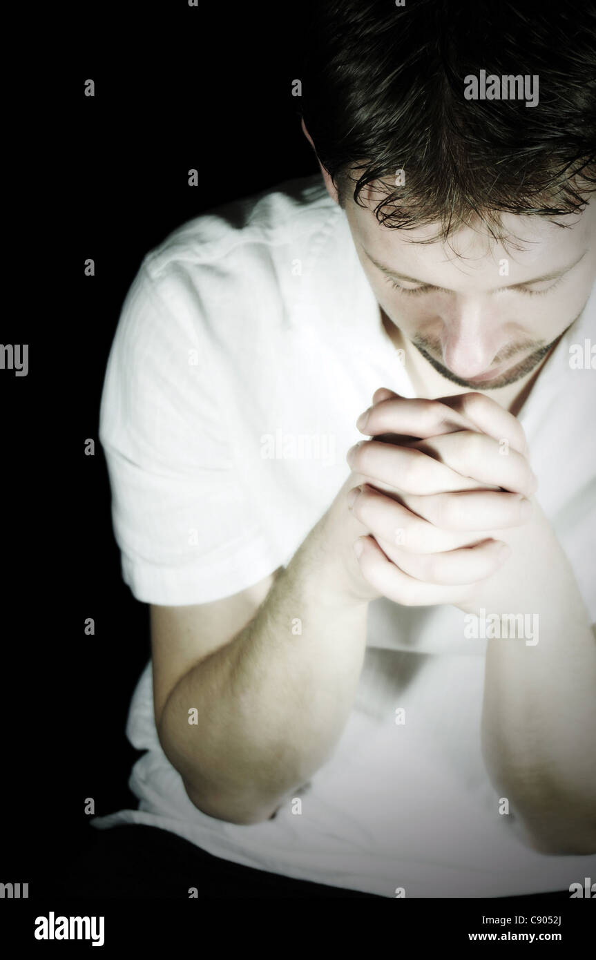 Young man praying in the dark Stock Photo Alamy