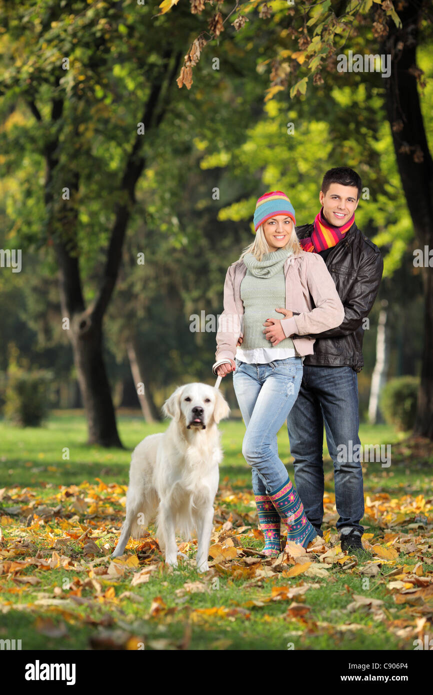 A smiling couple and their dog posing in the park in autumn Stock Photo ...