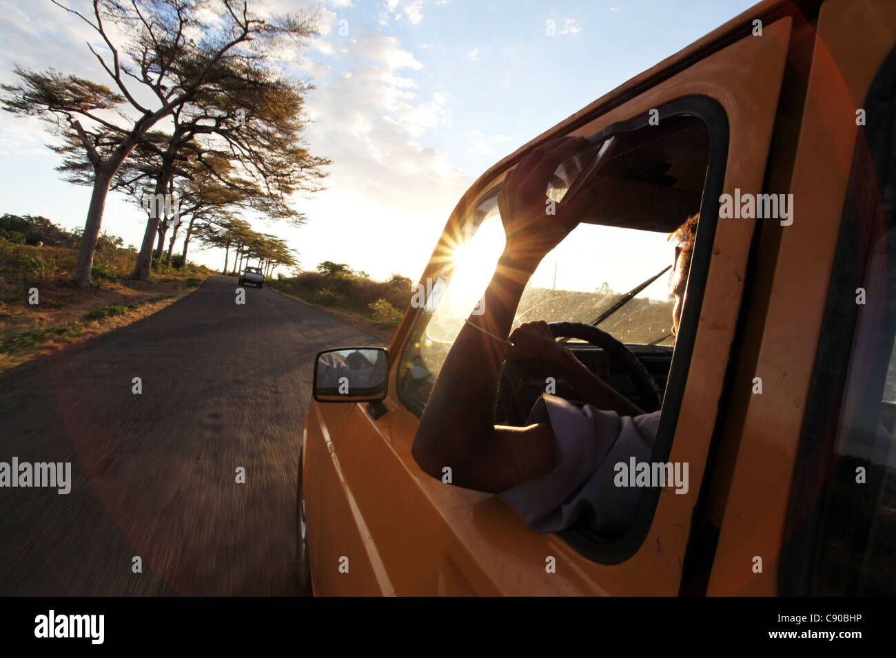 A taxi ride between Hell-Ville and Madirokely, Crater Bay, Nosy Be, Madagascar, with a star burst setting sun Stock Photo
