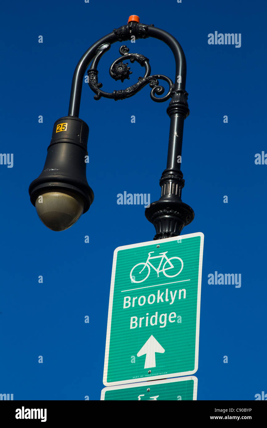 A lamppost and a sign showing the direction of the Brooklyn Bridge bicycle lane Stock Photo