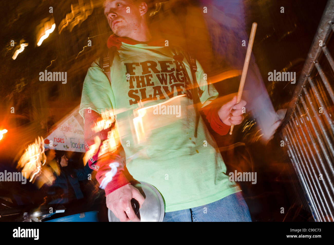 New York, NY -  6 November 2011 Anti Wall Street Protester wearing a free the wage slaves t-shirt plays the cymbals and the barricade in the drum circle of Liberty Square (Zuccotti Park ) Stock Photo