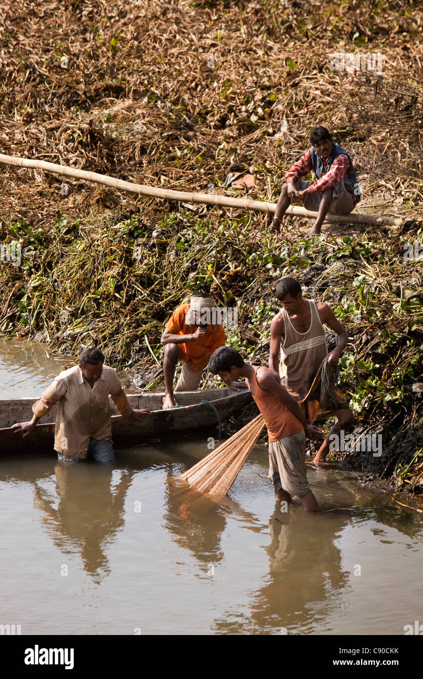 India, Assam, Majuli Island, fishernen fishing in tidal creek looking hopefully at net Stock Photo