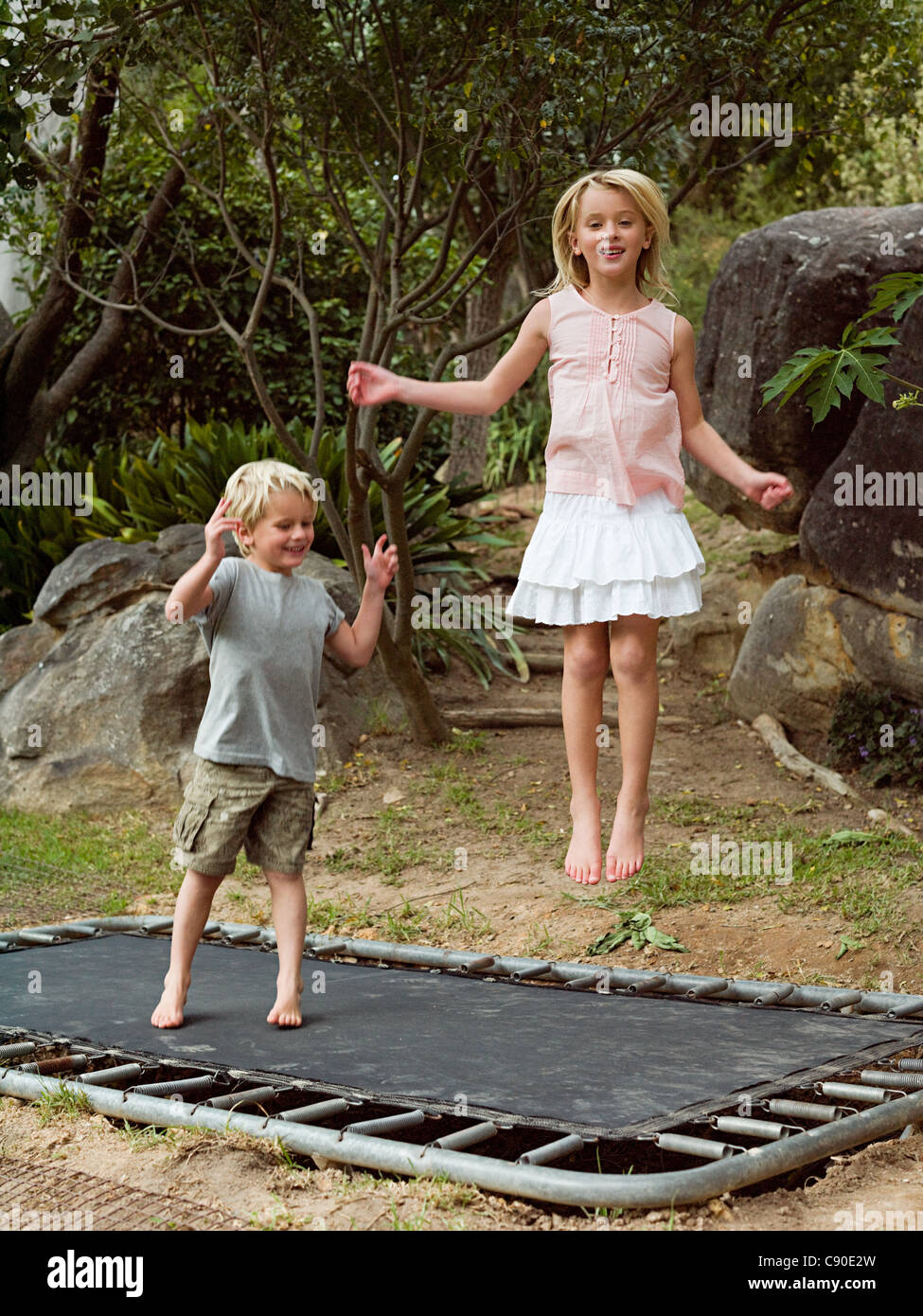 Brother and sister bouncing on trampoline Stock Photo