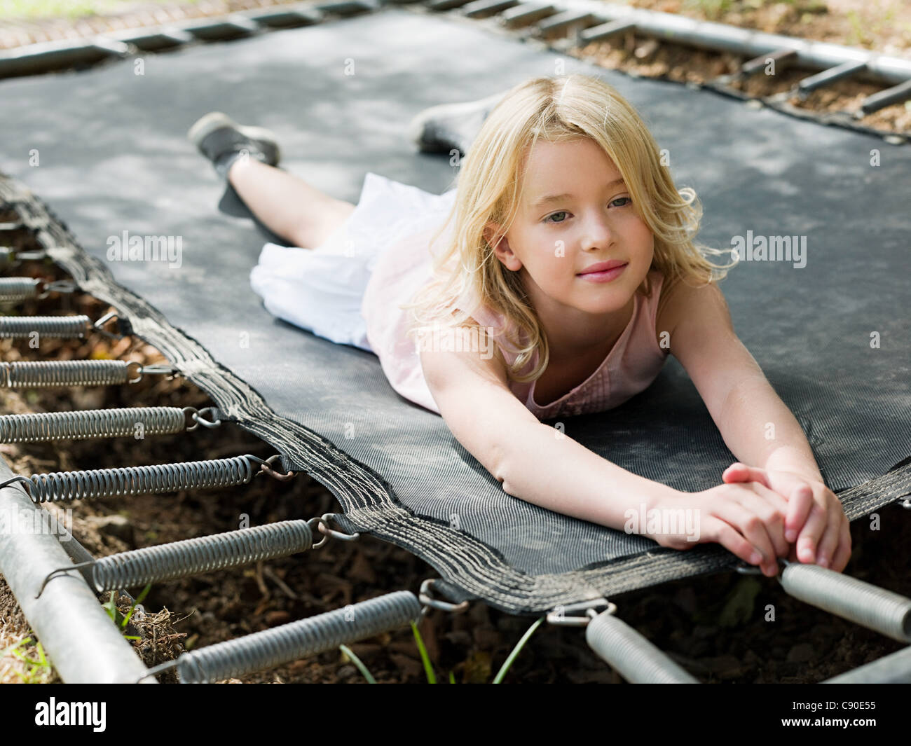 Girl lying on trampoline Stock Photo