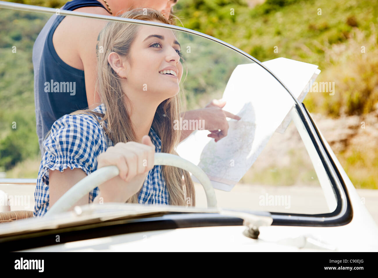Young people with convertible car looking at map Stock Photo