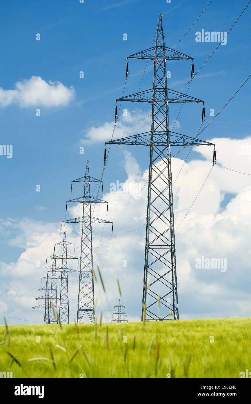 high voltage power lines in field against a blue sky Stock Photo - Alamy