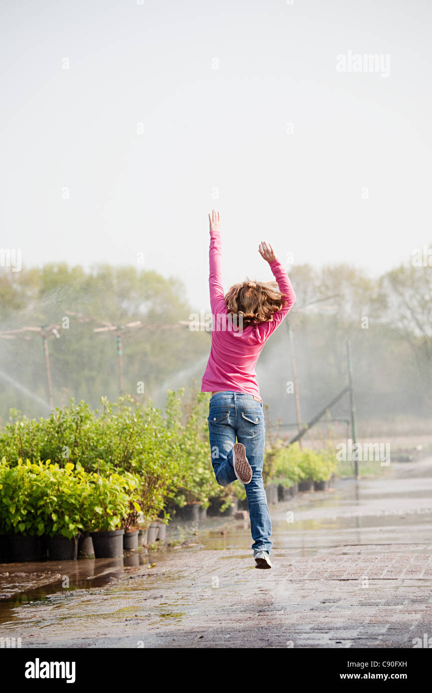 Girl skipping along path in plant nursery Stock Photo
