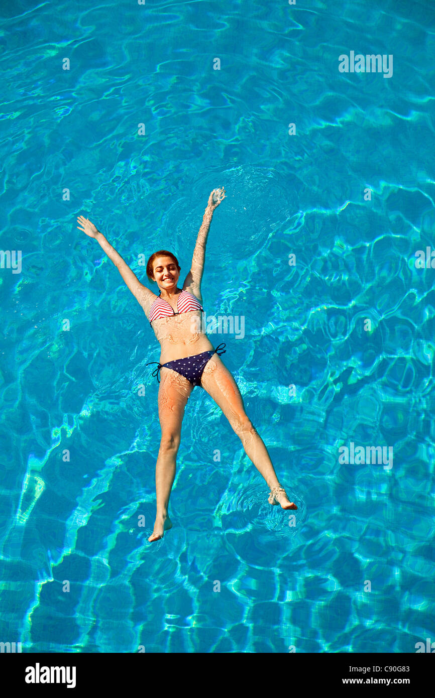 Young woman floating in swimming pool Stock Photo Alamy