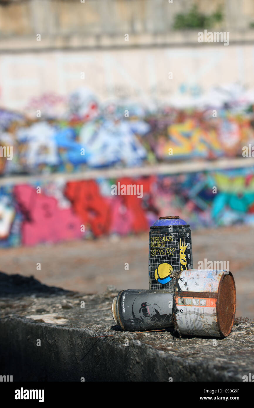 Discarded spray painting cans near a wall of Graffiti Stock Photo - Alamy