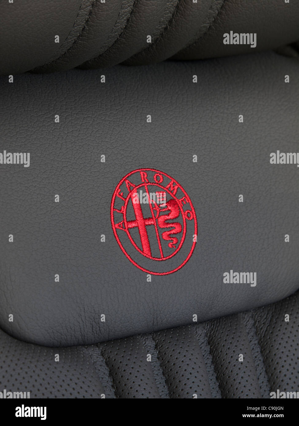 Alfa Romeo logo embroidered in red on a black leather car seat. Stock Photo