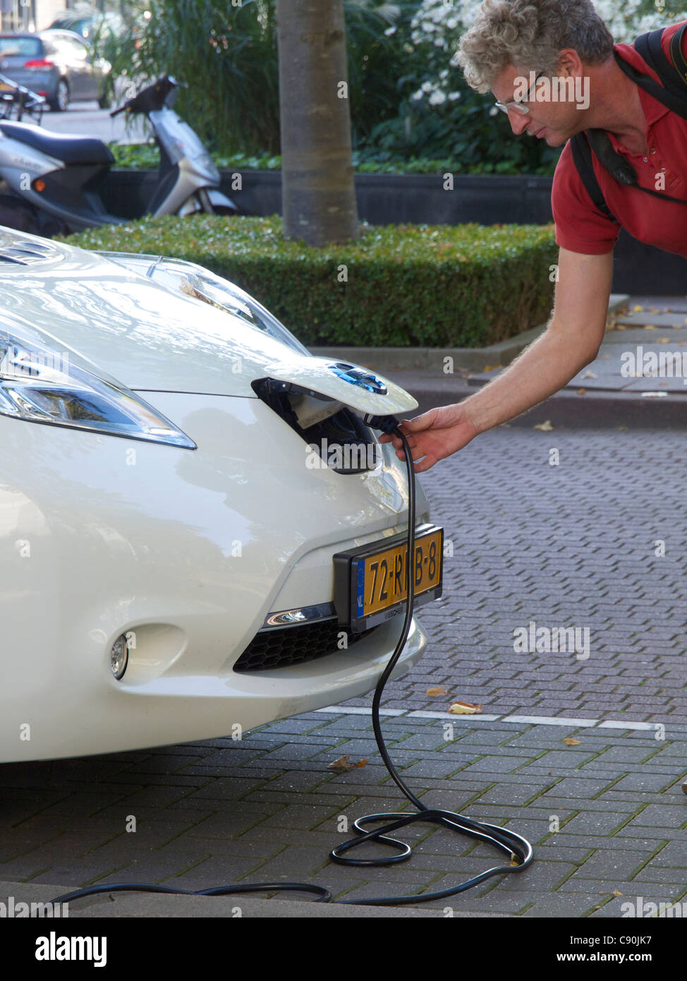 Man plugging in his Nissan Leaf electric car, Amsterdam, the Netherlands Stock Photo
