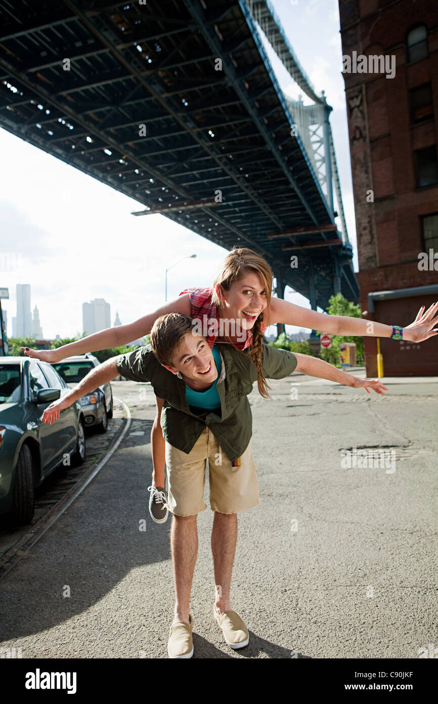 Young man carrying woman under bridge Stock Photo