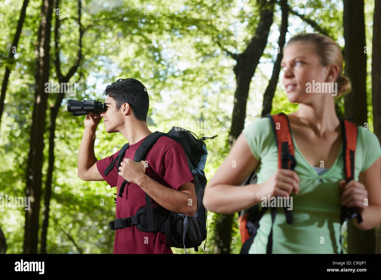young people trekking among trees and looking at birds with binoculars. Horizontal shape, side view, waist up Stock Photo