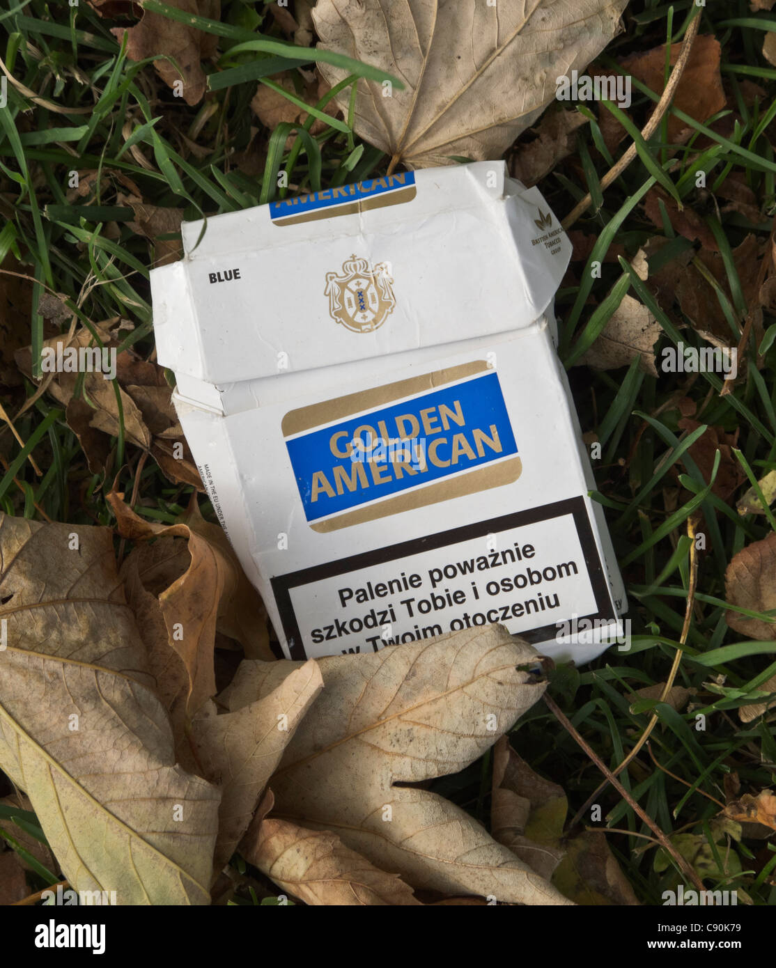 Worn empty Golden American cigarette packet on the ground. Warning text in  polish. FOR EDITORIAL USE ONLY Stock Photo
