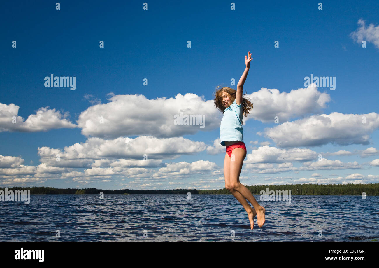 Nine year old girl jumping in the air at Boasjoen lake, Smaland, South Sweden, Scandinavia, Europe Stock Photo