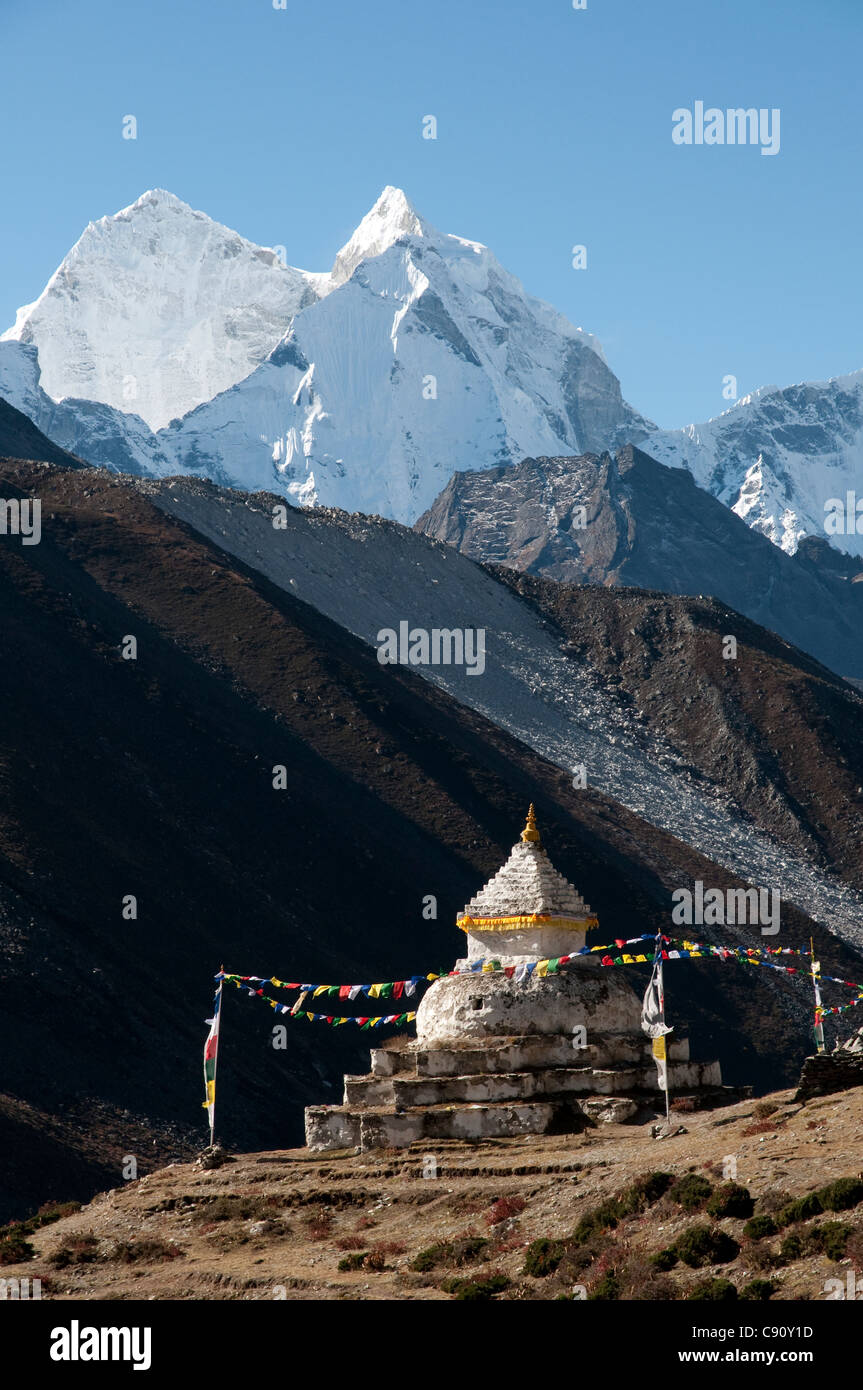 Thamserku peak towers over the route to Everest Base Camp in the Solu Khumbu region. There is a shrine beside the path with a Stock Photo
