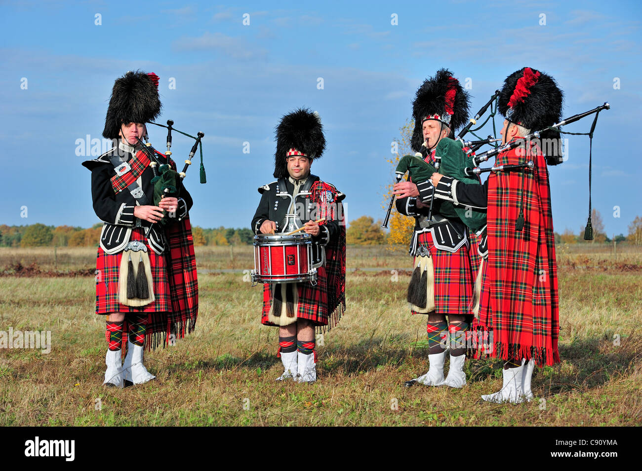 Scottish Highland bagpipers playing pipes and drums in moorland, Scotland, UK Stock Photo