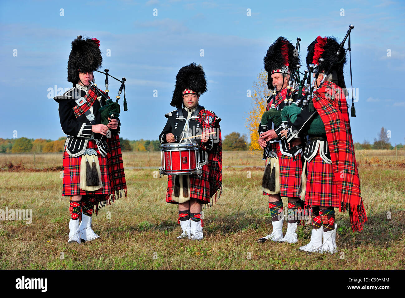 Scottish Highland bagpipers playing pipes and drums in heathland, Scotland, UK Stock Photo