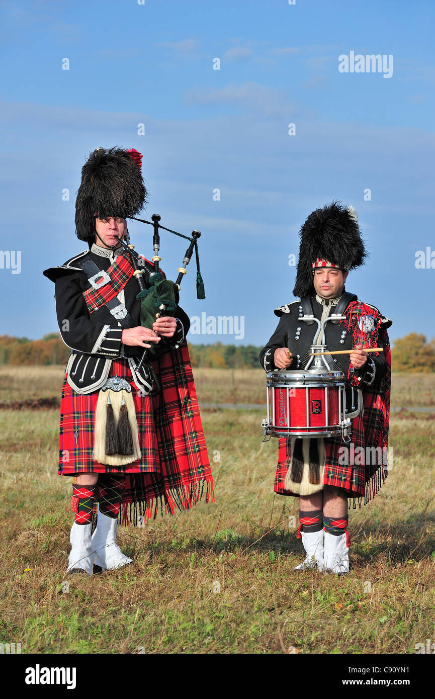 Scottish Highland bagpiper playing pipes and drums in heathland, Scotland, UK Stock Photo