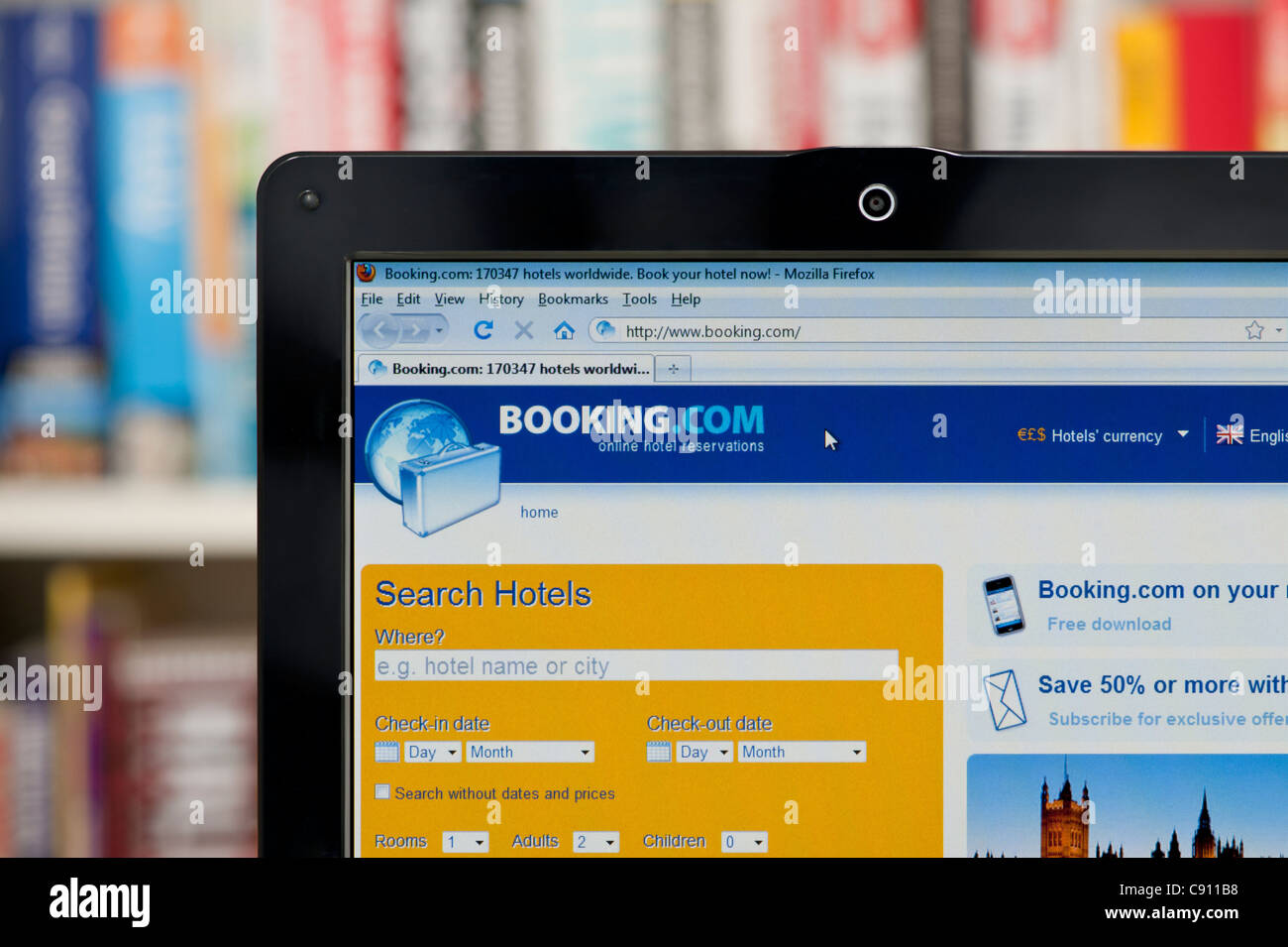The Booking.com website shot against a bookcase background (Editorial use only: print, TV, e-book and editorial website). Stock Photo