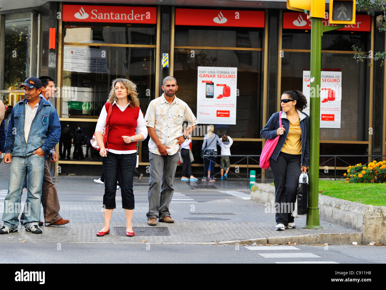 Pedestrians Waiting To Cross A Road Outside Of A Santander Bank In