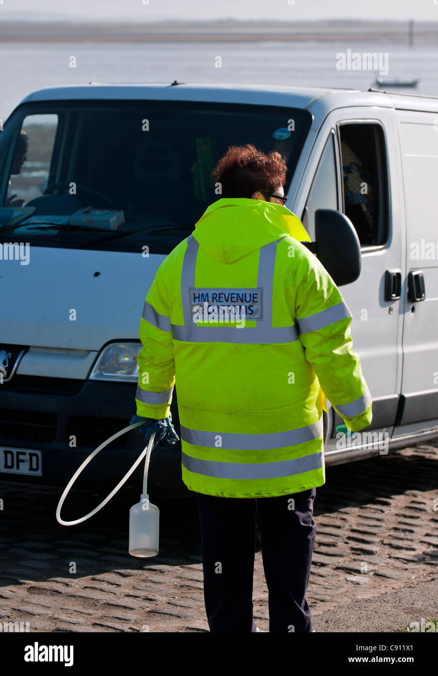 An officer from HM Revenue & Customs checking fuel in a van. Stock Photo