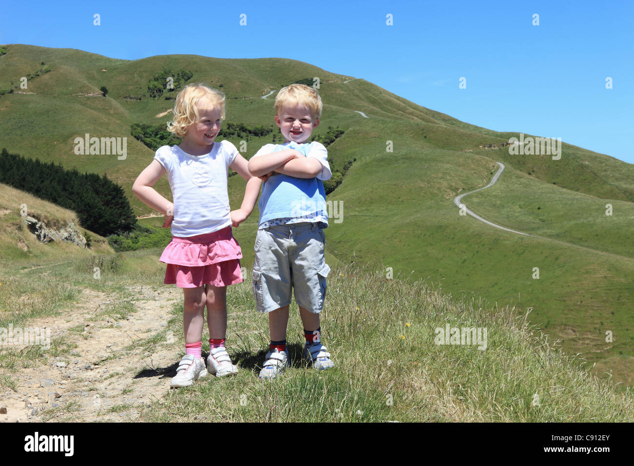 Being in the fresh air is good for children. Brother and sister standing outside in the sunshine. Stock Photo