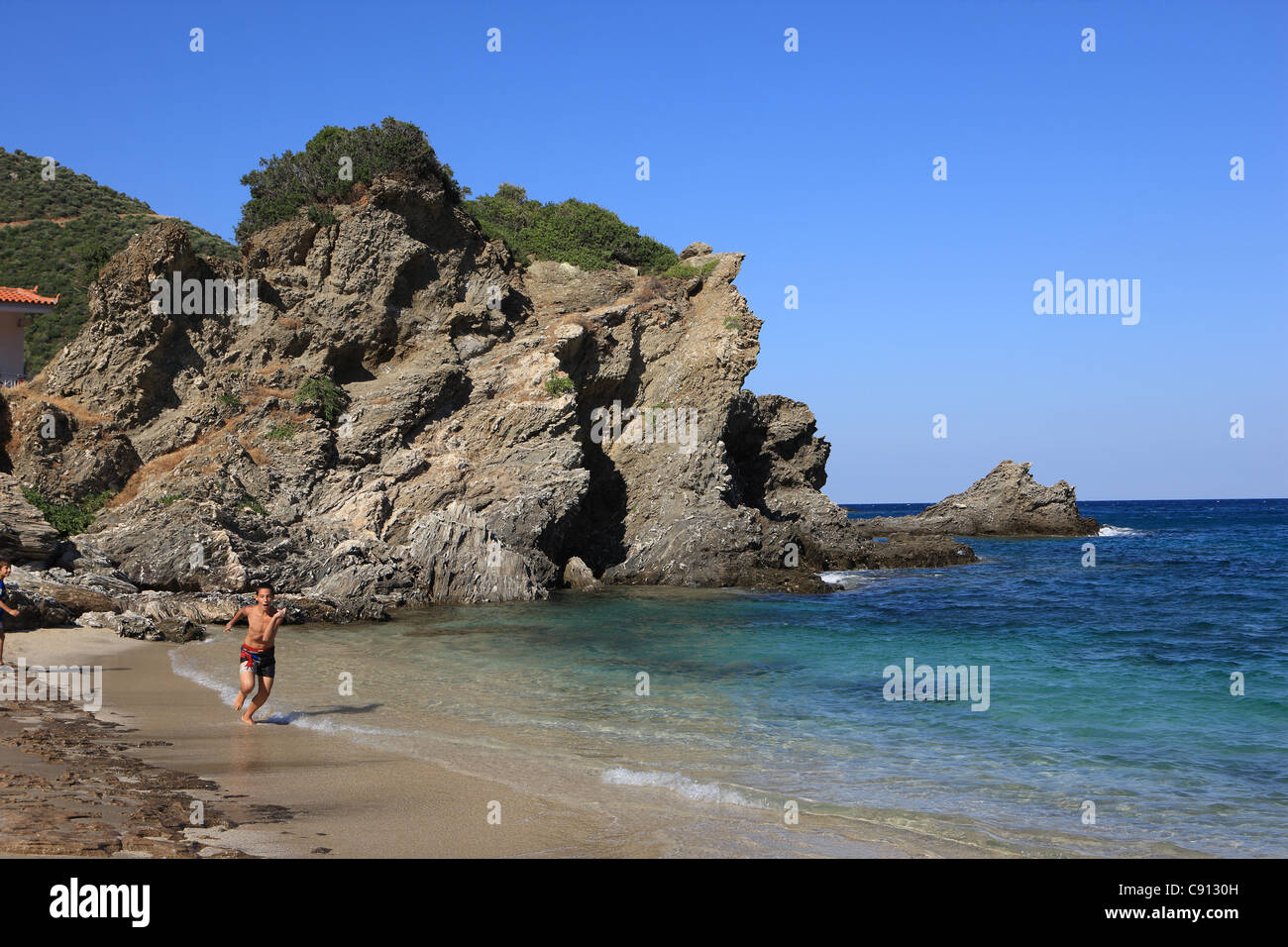 Boy running along the shoreline of Kalamos beach on the Greek island of Evia Stock Photo