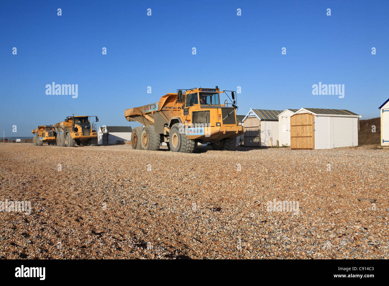 Large Volvo and Bell articulated dump trucks moving shingle, Norman's Bay, East Sussex, south coast, England, UK Stock Photo