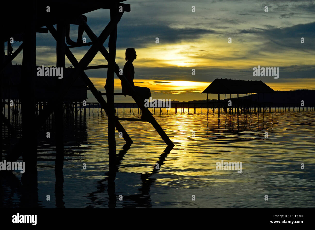 Woman silhouetted at sunset, Kri Eco Resort, Raja Ampat islands of Western Papua in the Pacific Ocean, Indonesia. Stock Photo